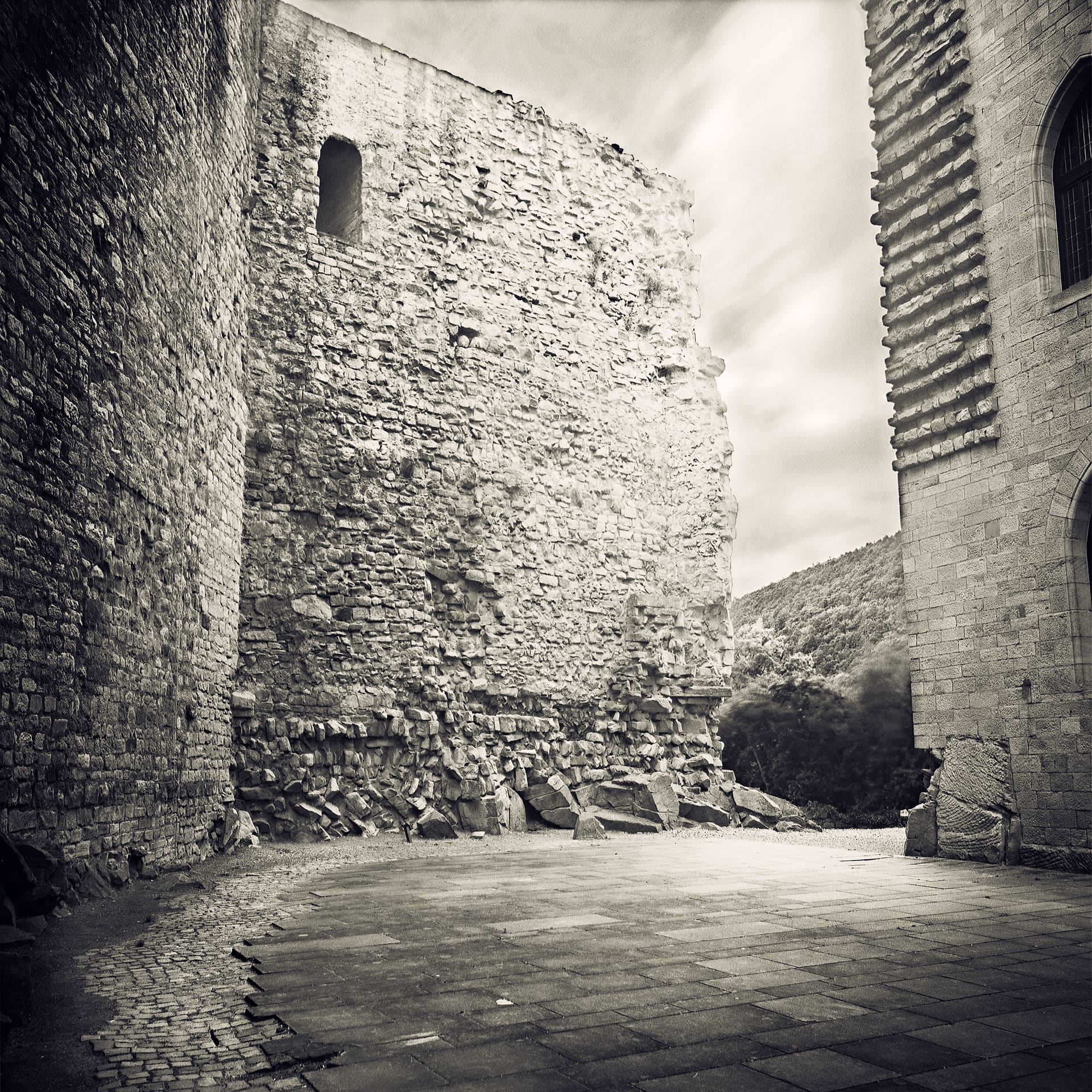 Ruined stone keep and rubble in an empty castle courtyard, cloud drawn out by a long exposure
